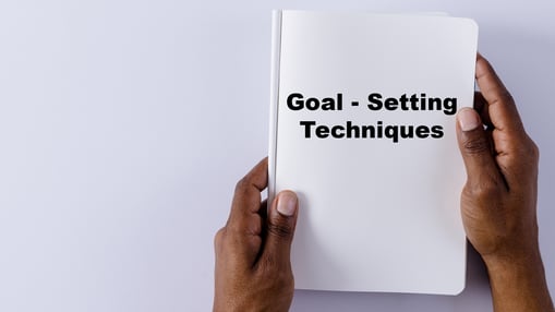 Close-up of a Hand Holding a Book on “Goal-Setting Techniques